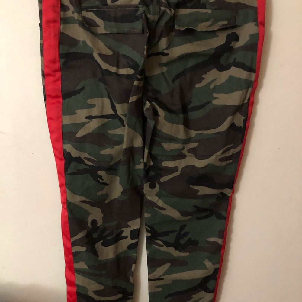 Waisted camouflage pants with red stripe .